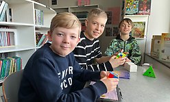 Tre mellanstadiekillar med kuber i händerna sitter vid ett  bord i skolbiblioteket på Nyvångsskolan.