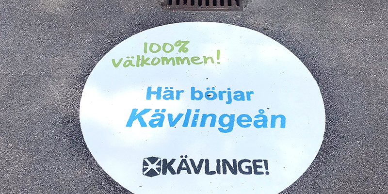 Klistermärke vid dagvattenbrunn med texten "Här börjar Kävlingeån"