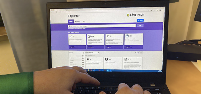 Två händer på ett tangentbord till en öppen, bärbar dator som är på webbplatsen för Kävlinge kommuns e-tjänster.