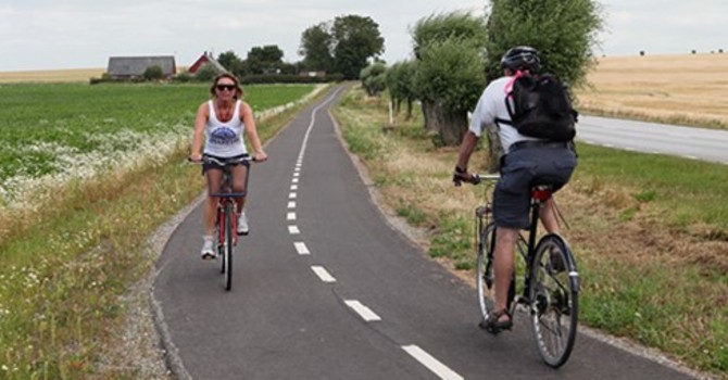 En man och en kvinna cyklar åt varsitt håll på en cykelväg i naturen