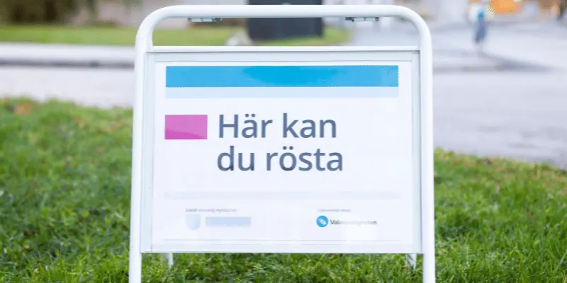 En skylt ed texten här kan du rösta står på en gräsmatta.