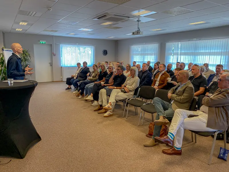 En minister står och pratar framför fyra stolsrader med lokala företagare