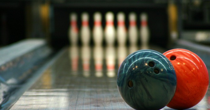 "two bowling balls focused and at the end, the pins waiting for the shot (with some grain for the lights)"