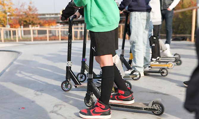 Flera barn som står med sina kickbikes.